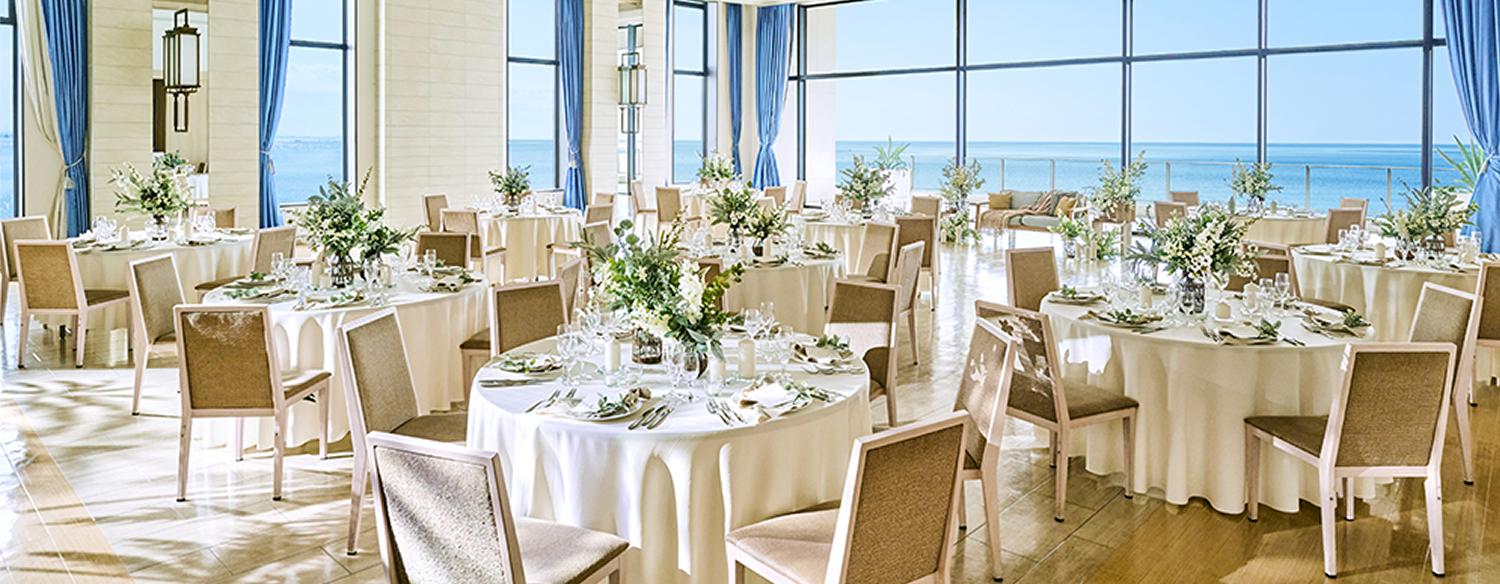 THE SURF OCEAN TERRACE(ザ・サーフ オーシャンテラス)。披露宴会場。白を基調としたリゾート感溢れる『リノ』。大きな窓いっぱいにきらめく海が広がる贅沢な空間です