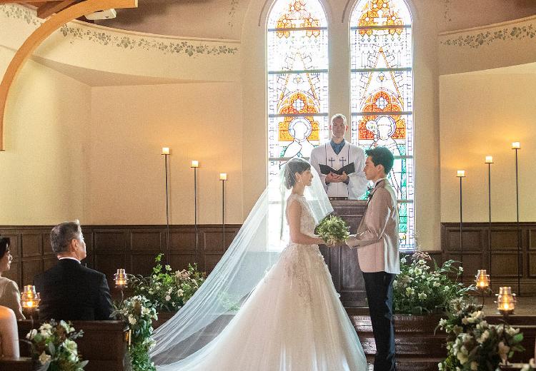 呉竹荘。挙式会場。ふたりの背景にはスペインの教会から譲り受けたステンドグラスが