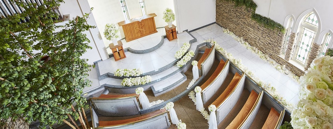 Only One Wedding サンパレス(オンリー ワン ウェディング サンパレス)。挙式会場。高い天井を誇る独立型チャペル。二人の姿がよく見えるように、カーブを描いたゲスト席を配しています