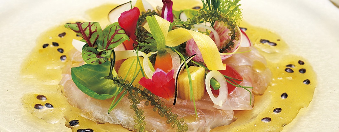 ザ・ブセナテラス。料理。海ブドウなど沖縄らしい食材や新鮮な魚介類を堪能できる一皿。色鮮やかな盛り付けが南国の雰囲気を演出します